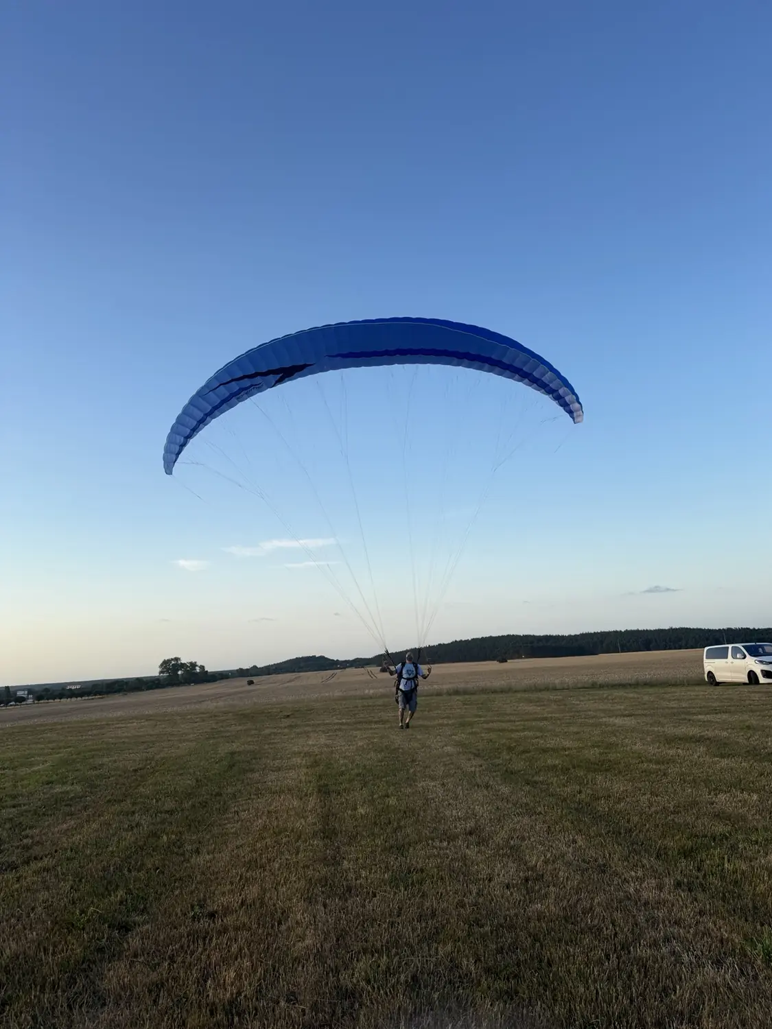 Frank von hinten unter seinem geöffneten blauen Gleitschirm